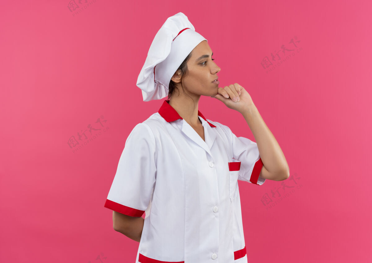 侧面站在剖面图年轻女厨师穿着厨师制服把手放在下巴与复制空间穿厨师放