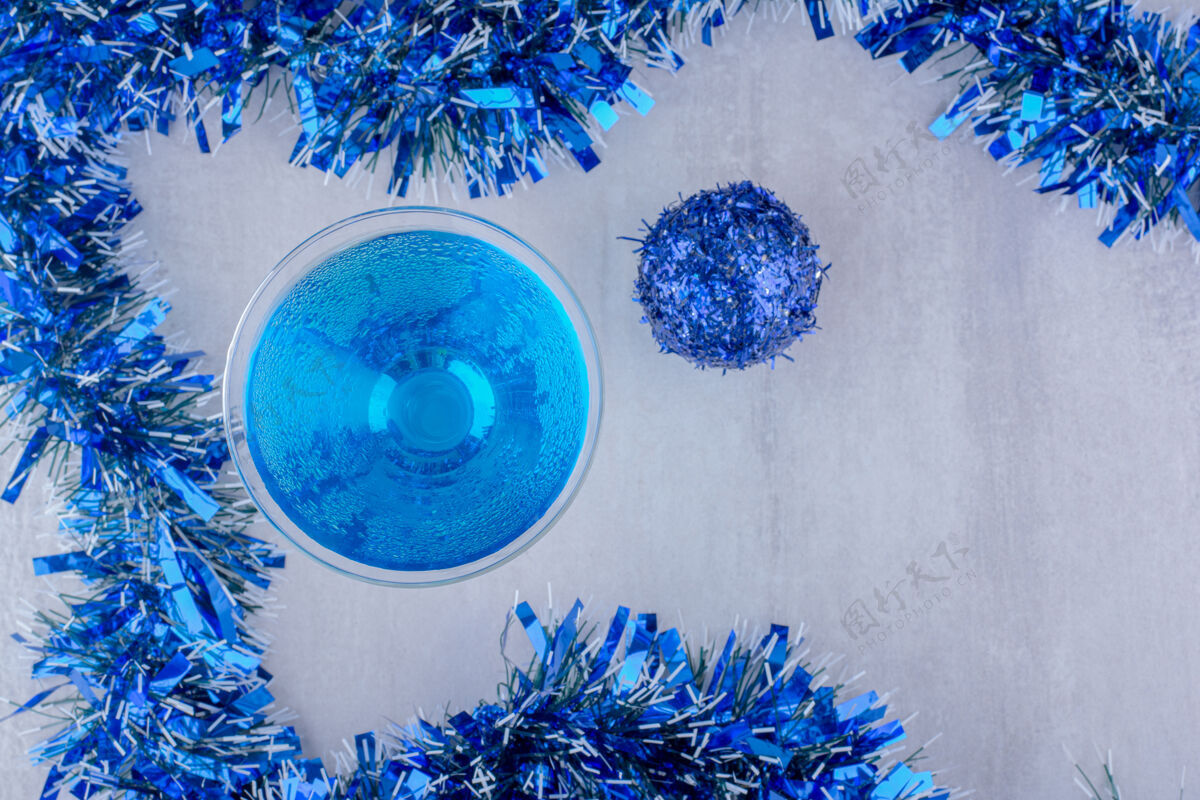 构图在白色背景上布置鸡尾酒杯和蓝色圣诞装饰装饰花环主题