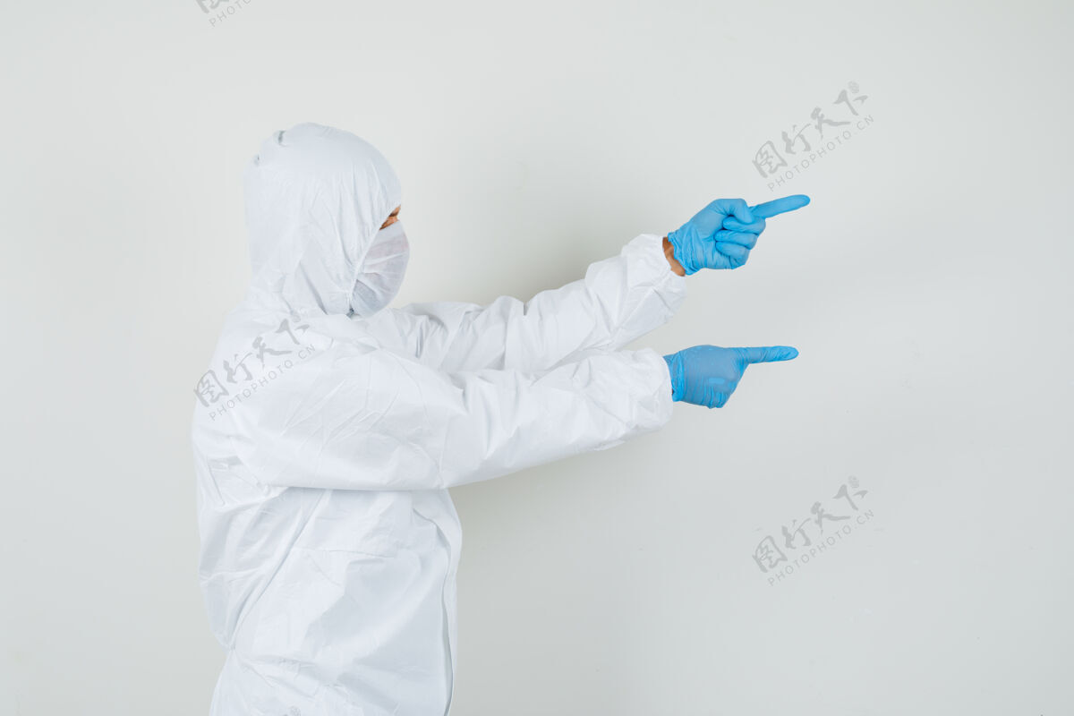 工作场所男医生穿着防护服指着侧面面罩专业人士手套