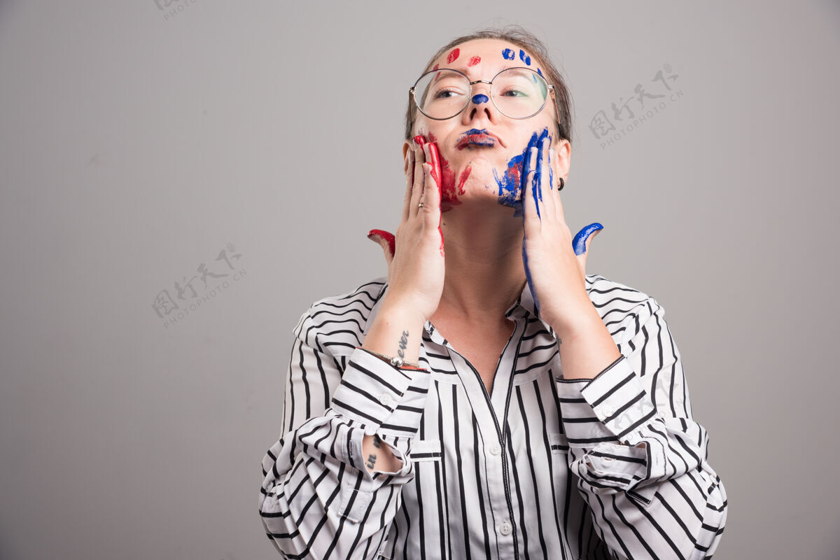 眼镜在灰色背景上 一个女人在脸上摆着颜料高质量的照片艺术家人手