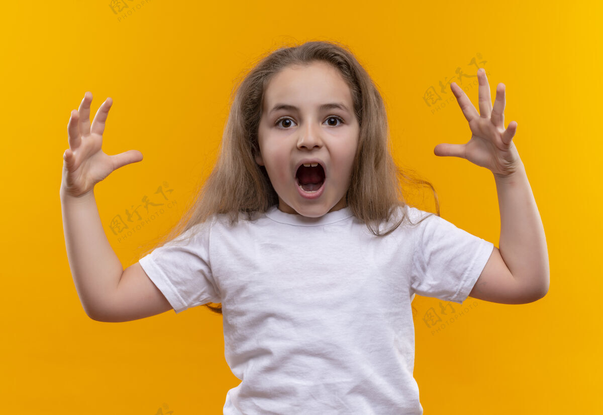 小一个穿着白色t恤的受惊的小女生在孤立的橙色背景上摊开双手女孩学校蔓延