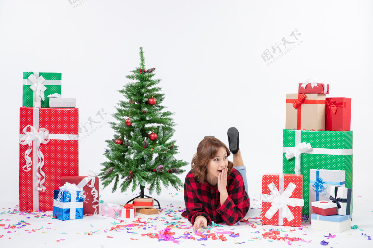 圣诞正面图年轻女性躺在圣诞礼物和圣诞树周围 背景是白色的圣诞新年礼物 颜色是雪树女性雪