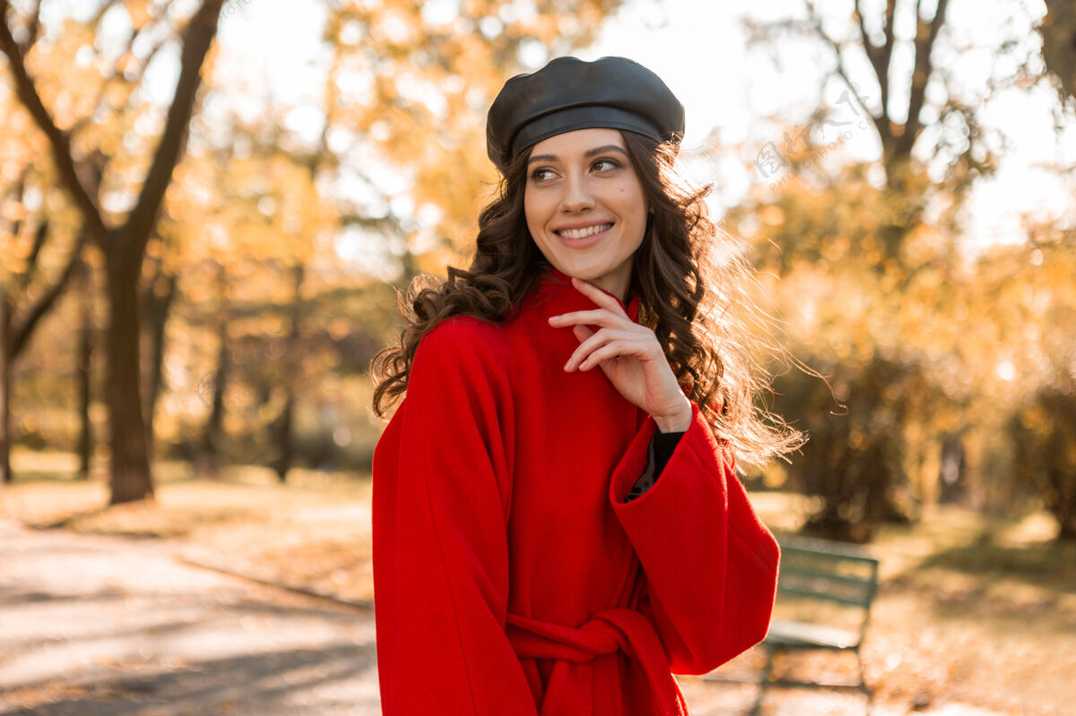 时尚迷人的时尚微笑的女人卷发漫步在公园穿着温暖的红色外套秋季时尚 街头风格 戴贝雷帽漂亮时尚年轻