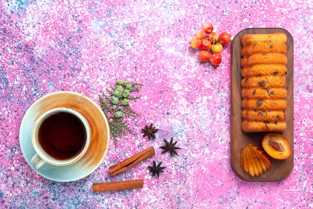茶托俯瞰美味的蛋糕 香甜可口 粉红色的桌子上放着李子和一杯茶美味茶甜点
