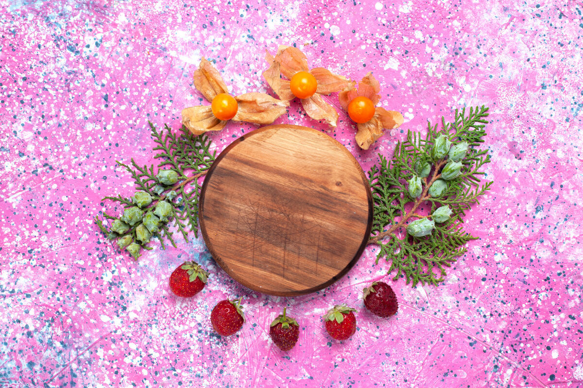 石南粉红色书桌上的新鲜红草莓和酸浆顶部紫色维管植物