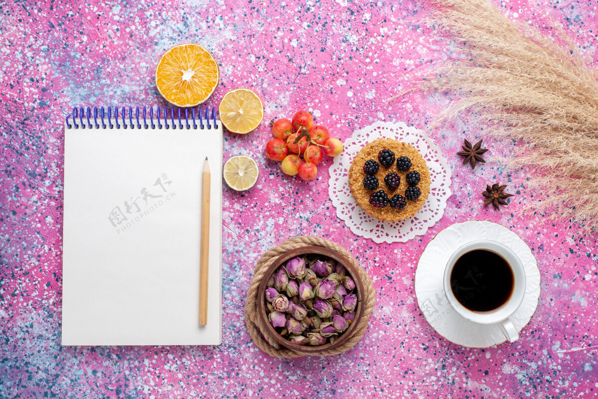 茶顶视图一杯茶 粉红色背景上有小蛋糕和记事本饼干粉色花