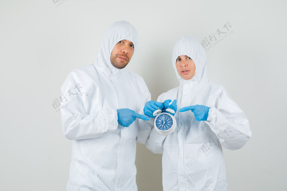 工作场所两个穿着防护服指着闹钟的医生职业人医院