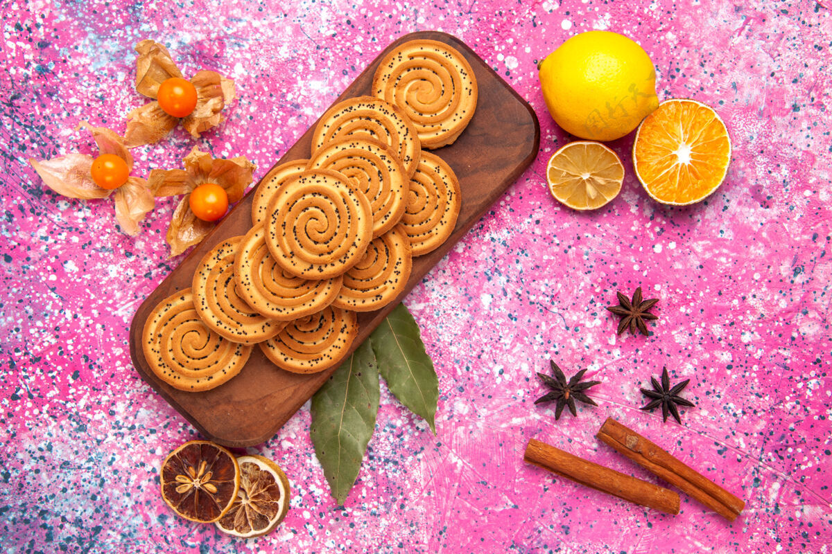 装饰品粉红色表面上点缀着肉桂和柠檬的圆形甜饼俯视图季节性美味茶