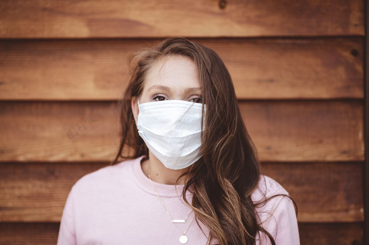 防护女人戴着卫生口罩在一堵木墙前木制卫生流行病