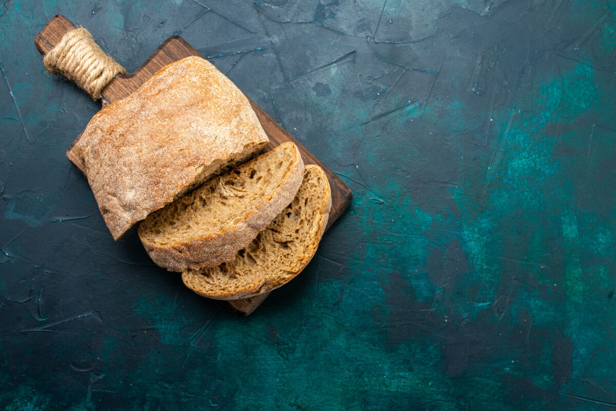 面包前视图面包面包美味烘焙和切片在深蓝色的桌子上棕色正面切片