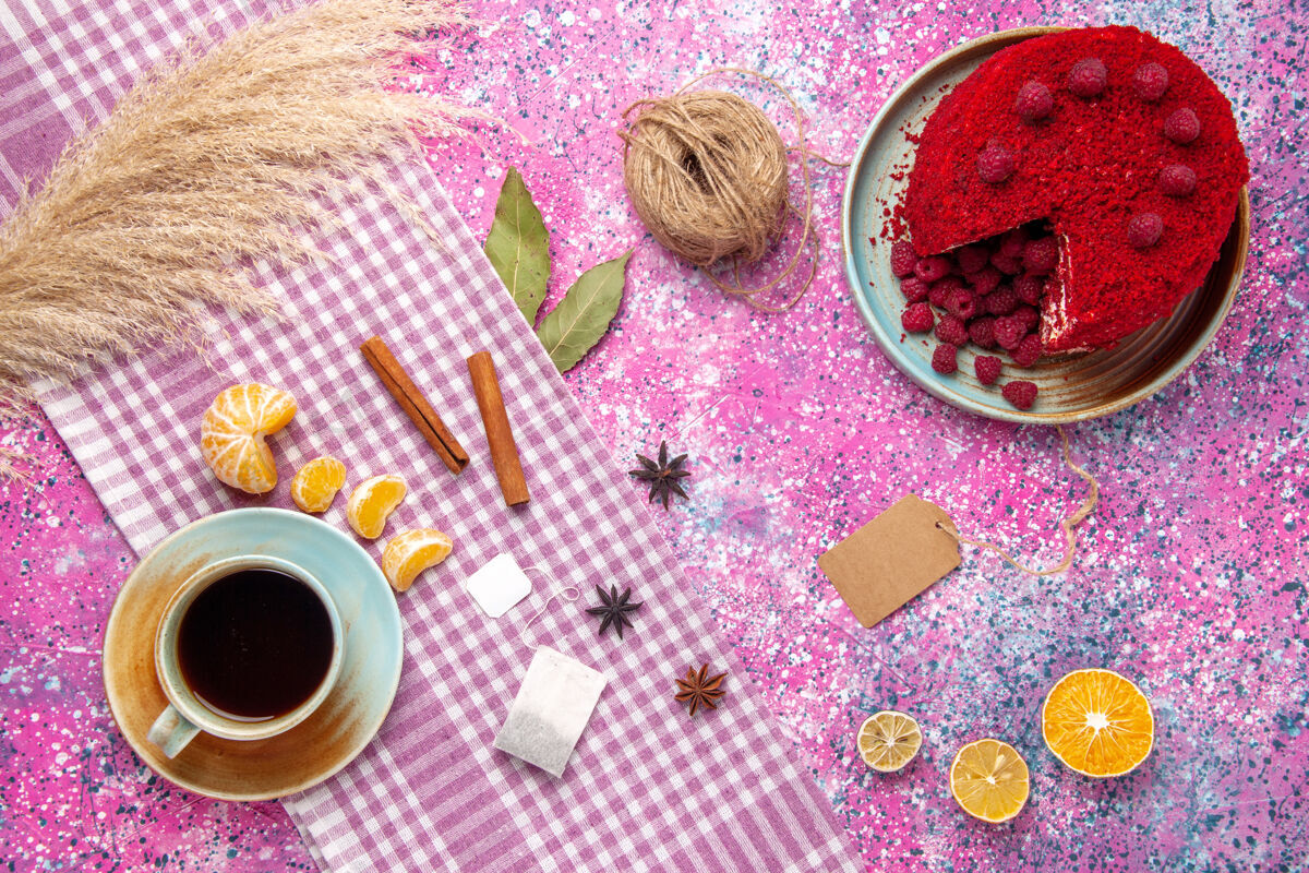 粉红色覆盆子蛋糕和肉桂橘子的俯视图 粉色表面上有一杯茶食品脸粉橘子