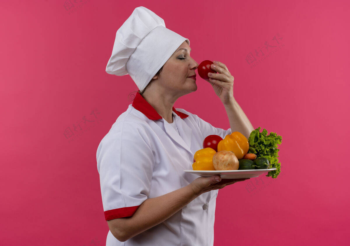 厨师站立侧视图身着厨师制服的中年女厨师手拿蔬菜盘嗅西红柿制服嗅简介