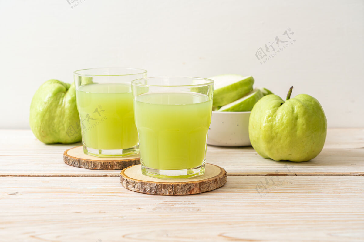 农业木桌上放着新鲜番石榴汁杯和新鲜番石榴水果营养美味绿色
