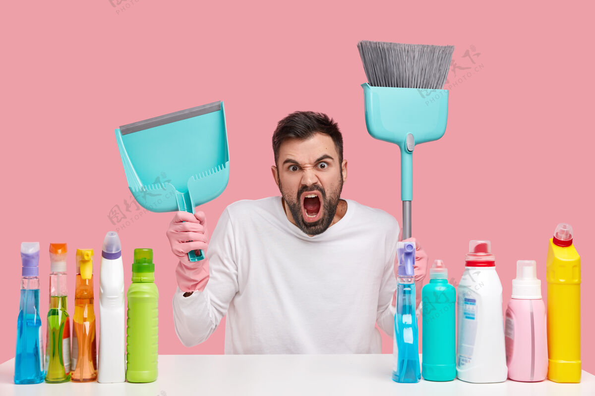 脏愤怒恼怒的没刮胡子的男人忙着打扫屋子 拿着勺子和扫帚 坐在桌子旁喷着清洁喷雾家务家务房子