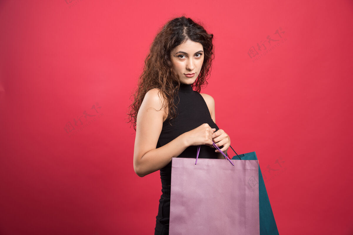 包一个目光狡猾的女人拿着红色背景的袋子看包女