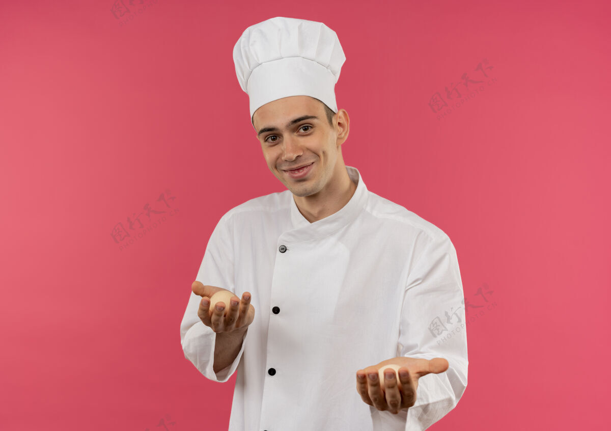 制服高兴的年轻男厨师穿着厨师制服拿着鸡蛋男厨师拿着