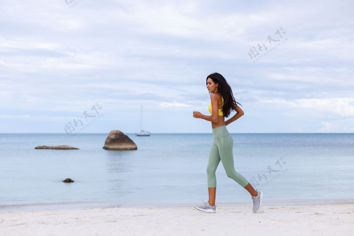 运动装海滩上穿着五颜六色运动服的迷人年轻女子减肥户外健康