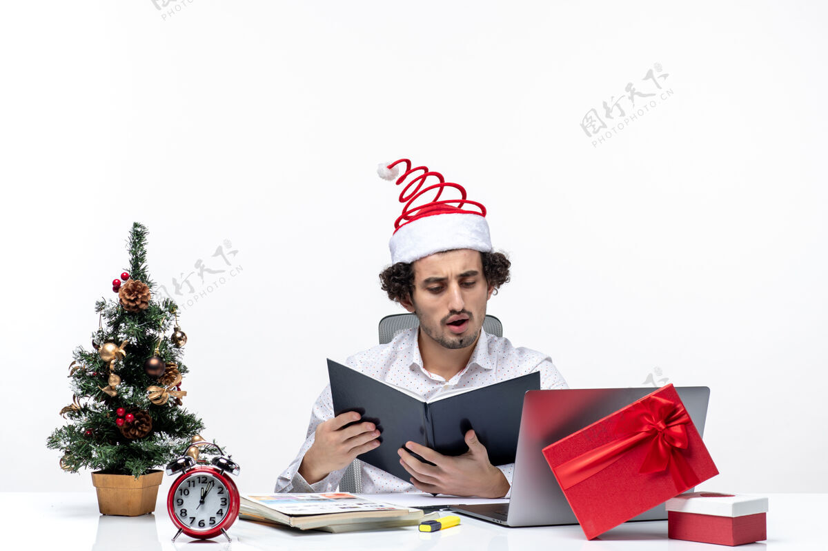 信息惊讶的年轻商人与有趣的圣诞老人帽子检查文件中的信息在白色背景的办公室工人文件人