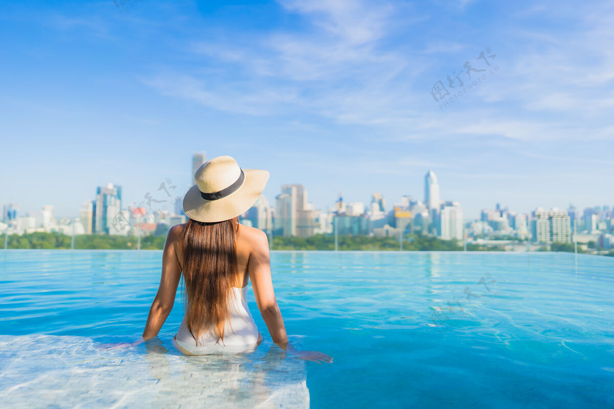 高美丽的亚洲年轻女子在户外游泳池周围放松 城市景色尽收眼底城市比基尼豪华