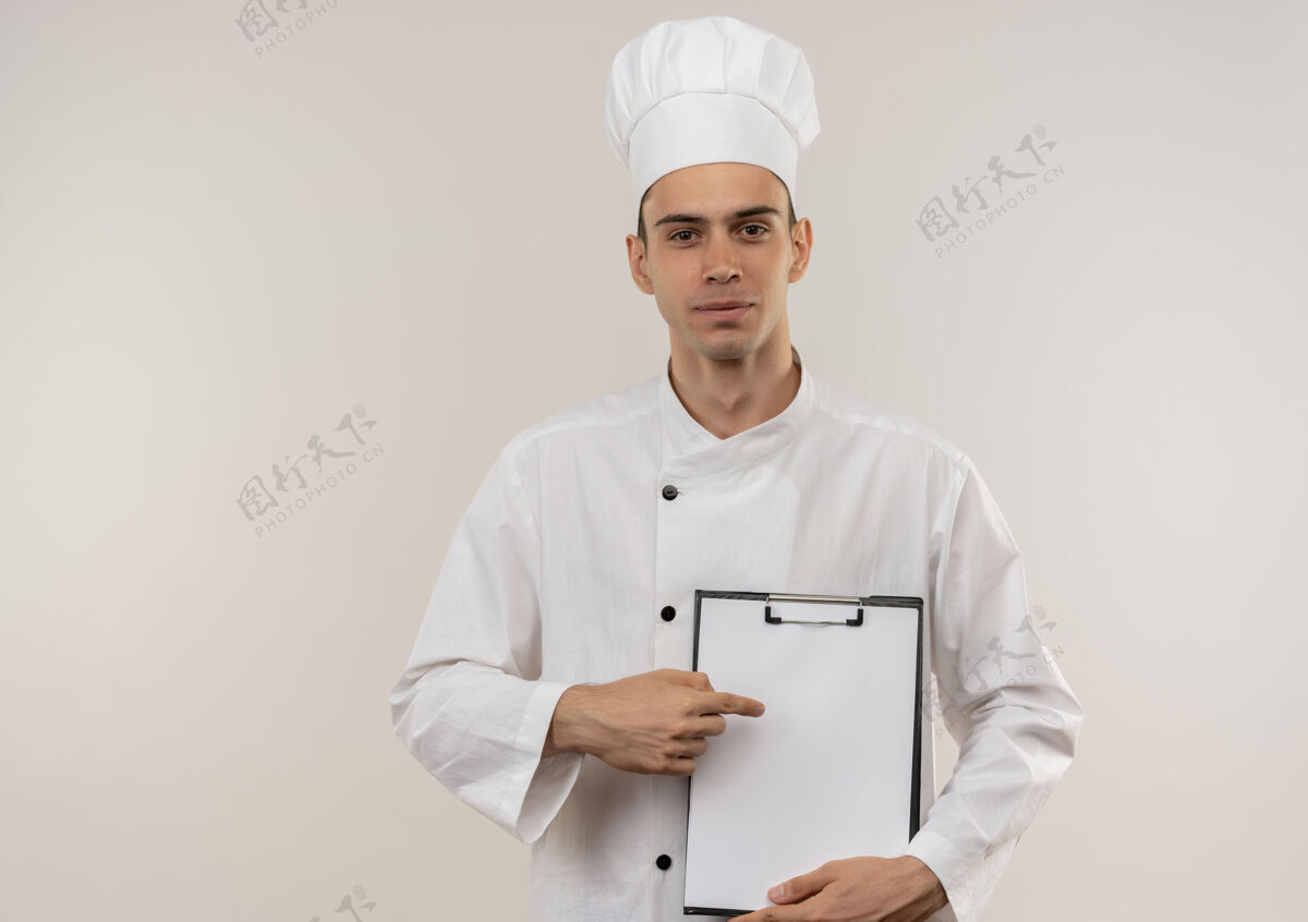 穿年轻的男厨师穿着厨师长的制服 高兴地用手指向他手中的剪贴板上抄空格厨师高兴厨师