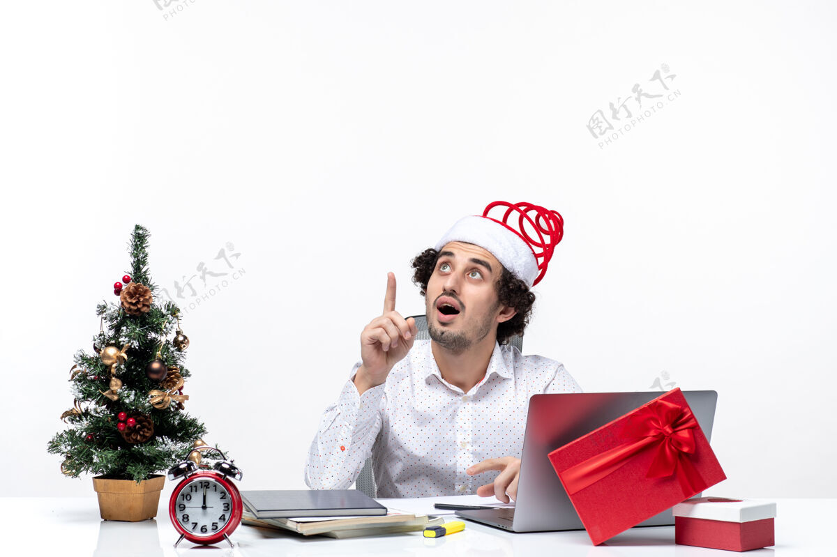 办公室满意的年轻商人与有趣的圣诞老人帽子看上面的想法和庆祝圣诞节在白色背景的办公室看微笑思考