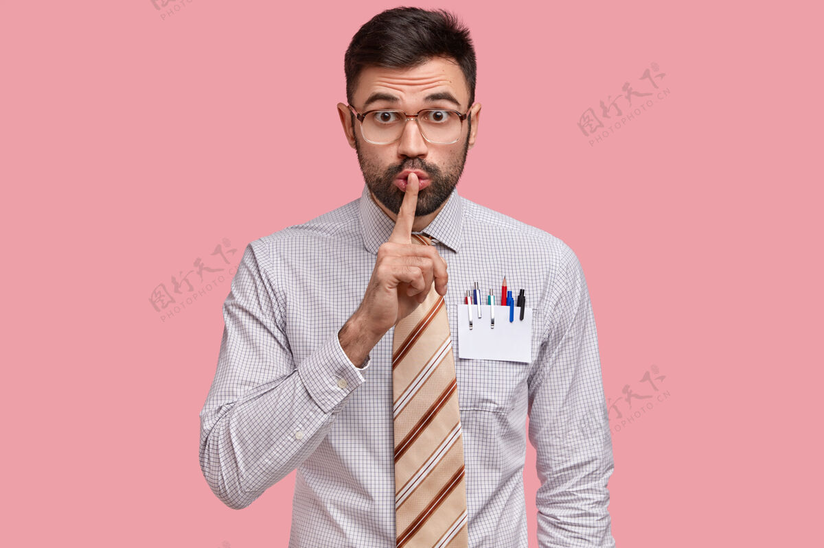 机密男设计师手指头贴在嘴唇上 穿着正装 衬衫口袋里有一张空白卡片 上面有铅笔和钢笔工人八卦男人