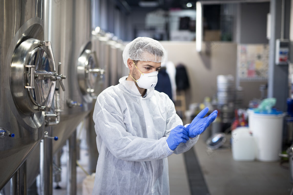 仓库年轻的技术员在生产工厂戴上橡胶防护手套制药专家控制