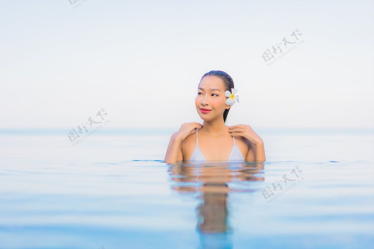 放松肖像美丽的亚洲年轻女子放松微笑周围的室外游泳池在酒店度假村日光浴度假村海滩
