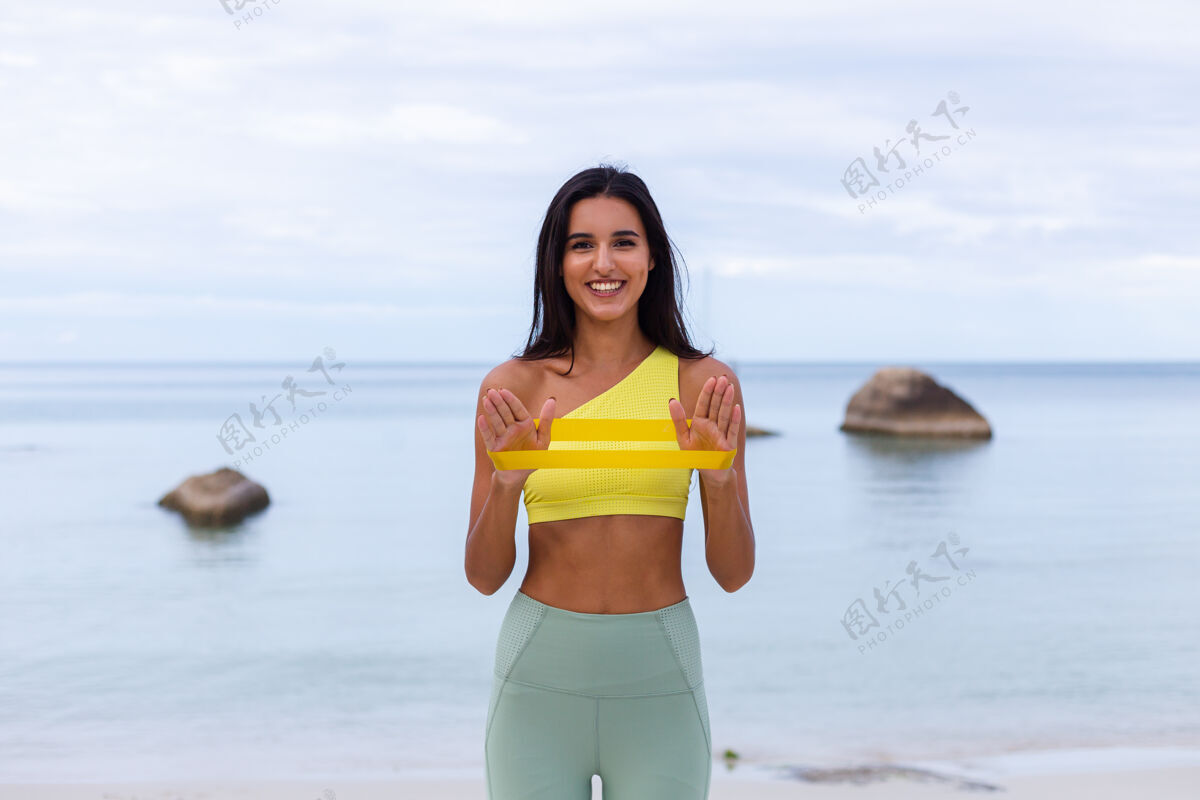 女人海滩上穿着五颜六色运动服的迷人年轻女子减肥活跃人