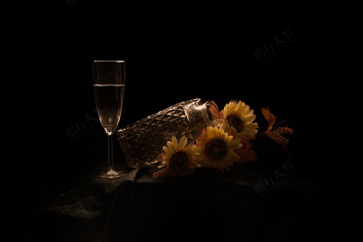 黑桌子上放着向日葵和香槟的罐子 背景是黑色的向日葵酒精开花
