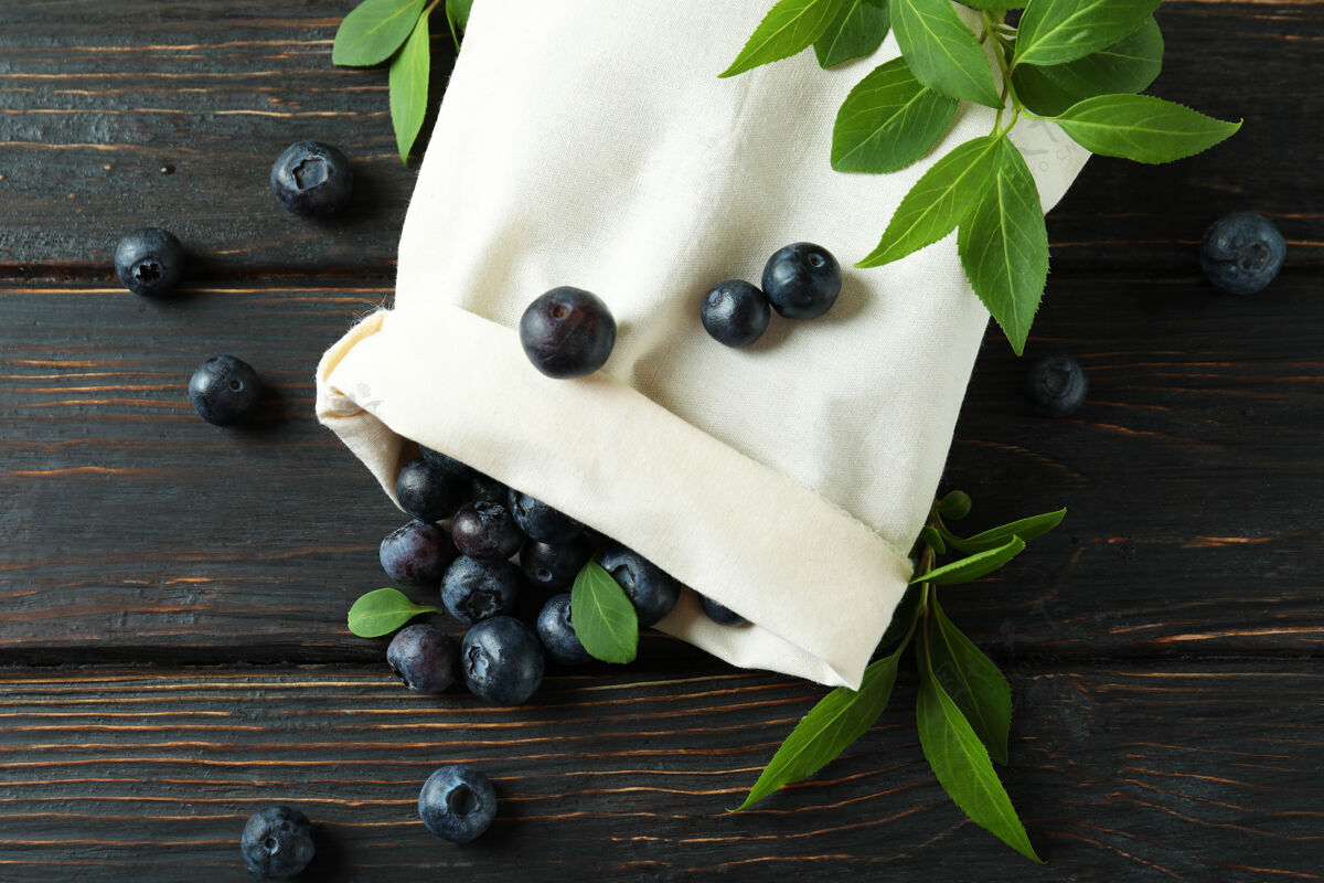 多汁新鲜的浆果概念和蓝莓放在木桌上叶子棉花宏